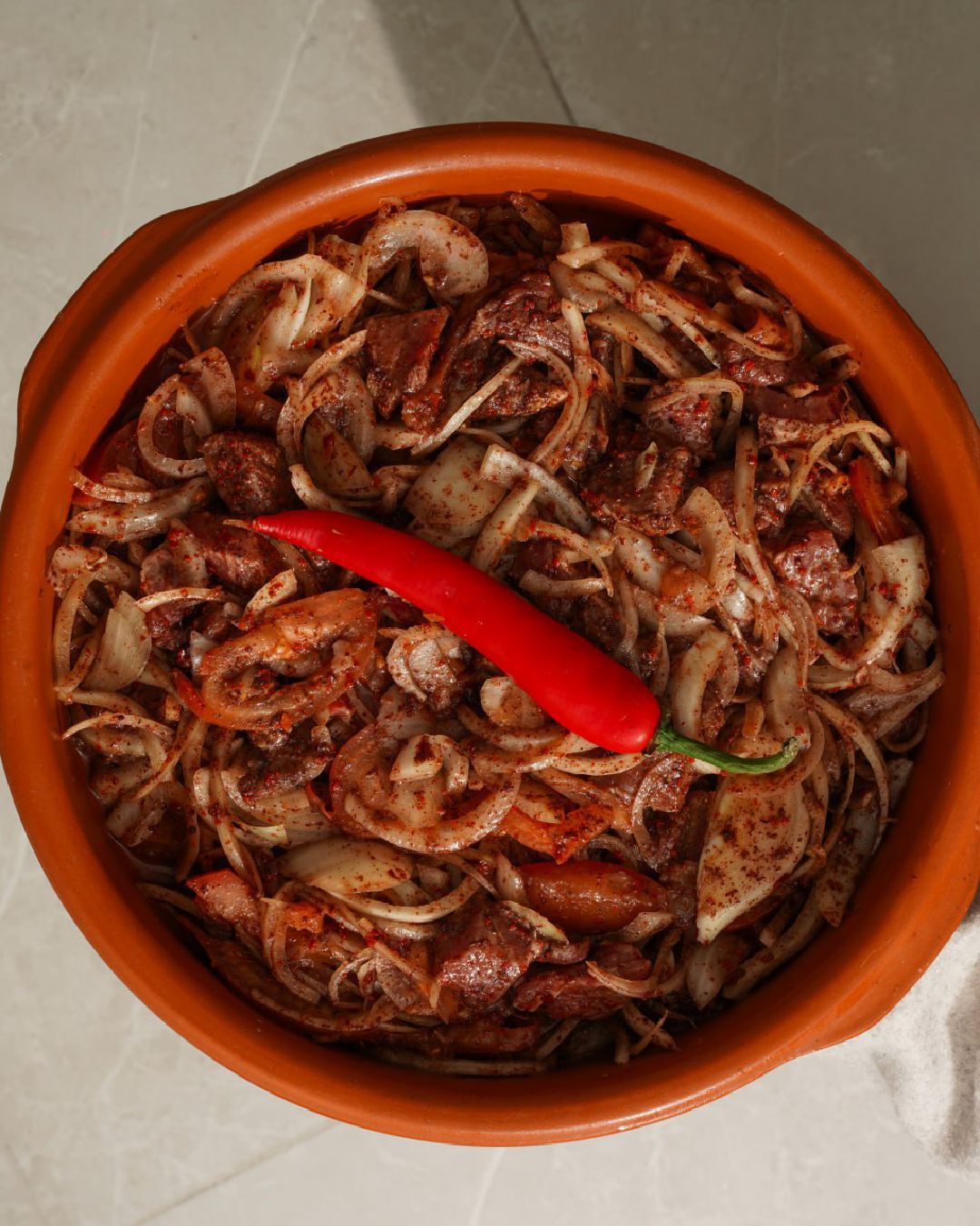 Spiced meat with onions and chili in clay pot